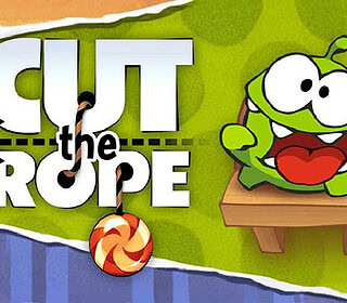Scissors cutting rope in a fun online puzzle game, "Cut the Rope", featuring a cute green character and candy.