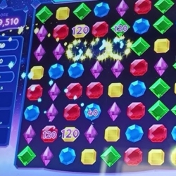 Bright colorful gem match-3 puzzle game with glowing effects and score display.